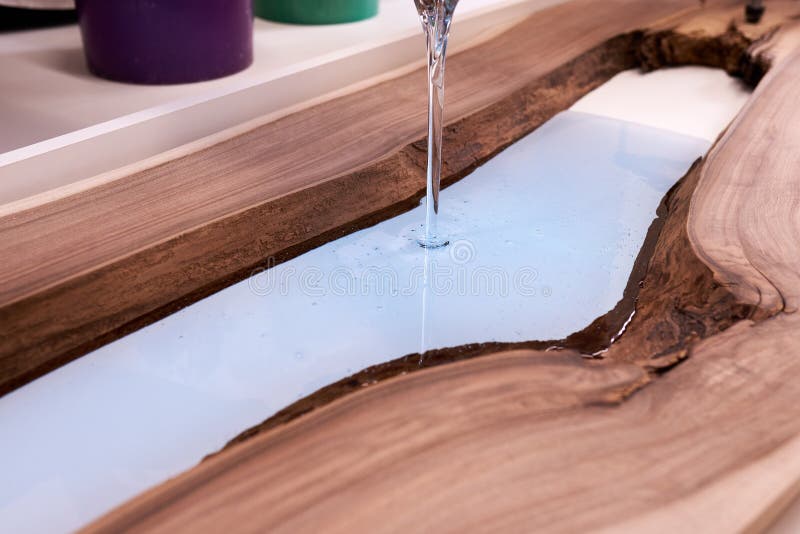 Process making of a craft resin and wood table. Liquid epoxy is poured into a mold with wooden blanks royalty free stock photo