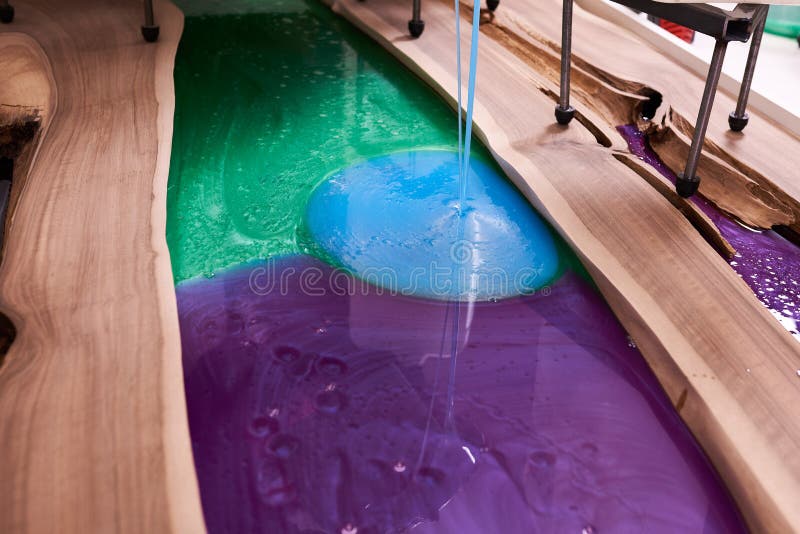 Process making of a craft resin and wood table. Liquid epoxy is poured into a mold with wooden blanks royalty free stock photos