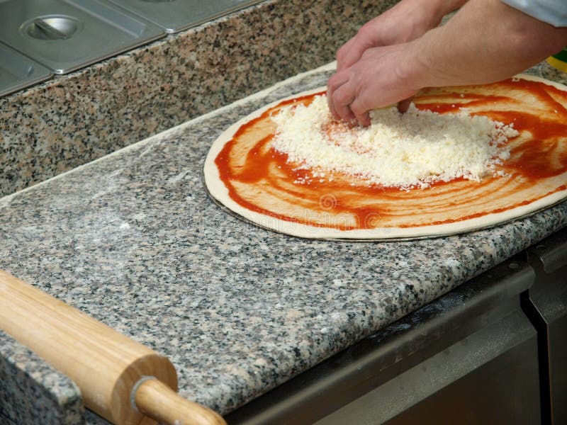 The Process of Making Italian Pizza. Chef Sprinkles Dough with Cheese