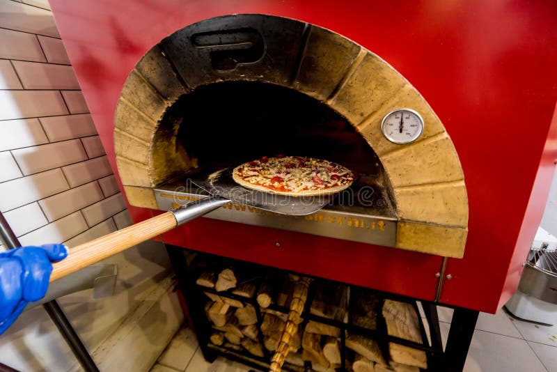 The Process of Making Pizza. Chef Baker Puts Raw Pizza in the Oven