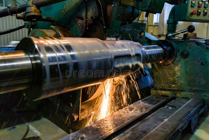 Processing and manufacturing of a shaft with an abrasive stone on a circular grinding machine, sparks are cooled by a liquid stock image