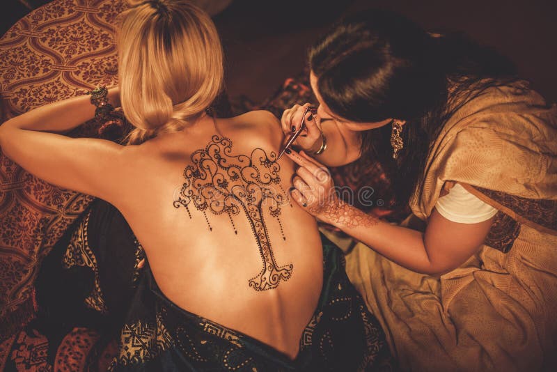 Drawing process of henna menhdi ornament on woman's back. Drawing process of henna menhdi ornament on woman's back