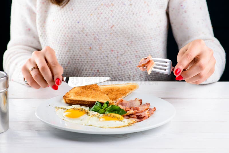 Processus de manger le petit déjeuner anglais savoureux avec des oeufs au plat, lard image stock Processus de manger le petit déjeuner anglais savoureux avec des oeufs au plat, lard image stock
