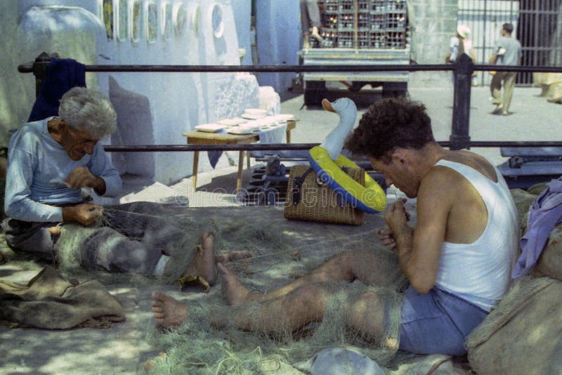 PROCIDA, ITALIË, herstellen 1972 - Twee vissers hun visnetten met vaardigheid en ervaring stock afbeeldingen PROCIDA, ITALIË, herstellen 1972 - Twee vissers hun visnetten met vaardigheid en ervaring stock afbeeldingen