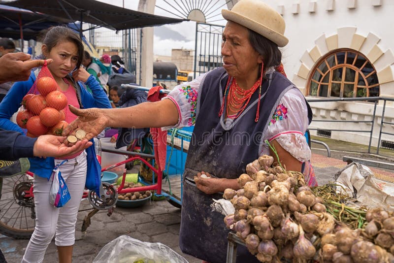 May 6, 2017 Otavalo, Ecuador: produce vendor in the Saturday market giving change to costumer. May 6, 2017 Otavalo, Ecuador: produce vendor in the Saturday market giving change to costumer