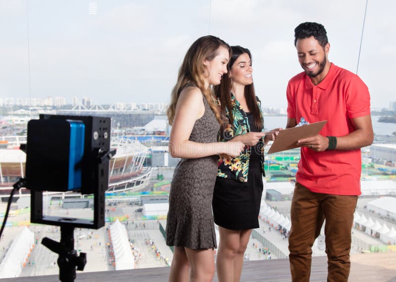 Producteur de télévision parlant avec les présentateurs féminins au sujet de l'exposition de TV image libre de droits Producteur de télévision parlant avec les présentateurs féminins au sujet de l'exposition de TV image libre de droits