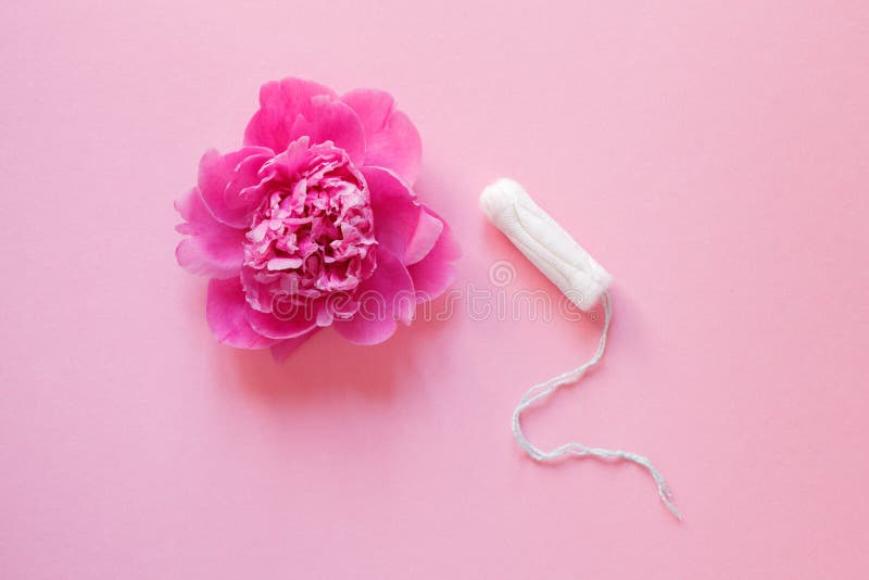 Producto de higiene íntimo de las mujeres, tapón y flor fresca hermosa de la peonía en el fondo rosado, disposición plana foto de archivo libre de regalías Producto de higiene íntimo de las mujeres, tapón y flor fresca hermosa de la peonía en el fondo rosado, disposición plana foto de archivo libre de regalías