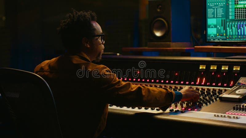 Producător muzical care operează consola de mixare în camera de control stock photos
