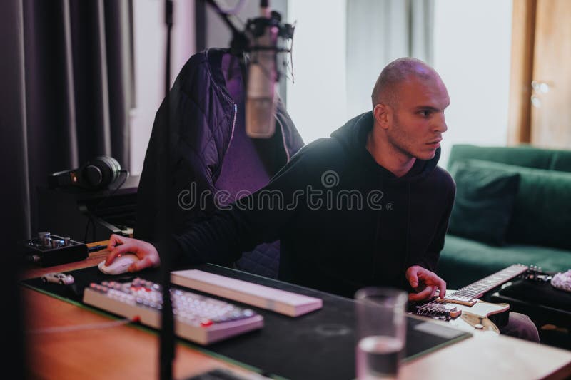 Producător muzical concentrat care lucrează într-un studio de înregistrare cu chitară și echipament stock photos