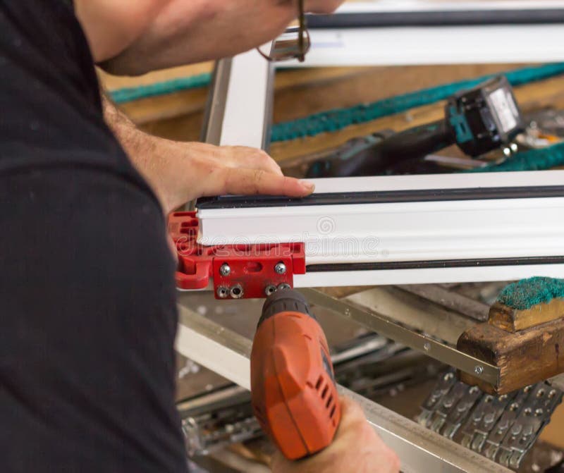 Produktion av pvc-fönster, en man skruvar en skruvmejsel in i ett pvc-fönster, närbilden, fönsterpvc arkivbild Produktion av pvc-fönster, en man skruvar en skruvmejsel in i ett pvc-fönster, närbilden, fönsterpvc arkivbild