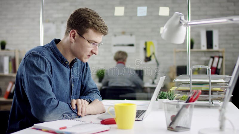 Produktiver starker ernster Geschäftsmann, der zurück Fertigungsbüroarbeit auf Laptop, effektiver Manager erfüllt lehnt