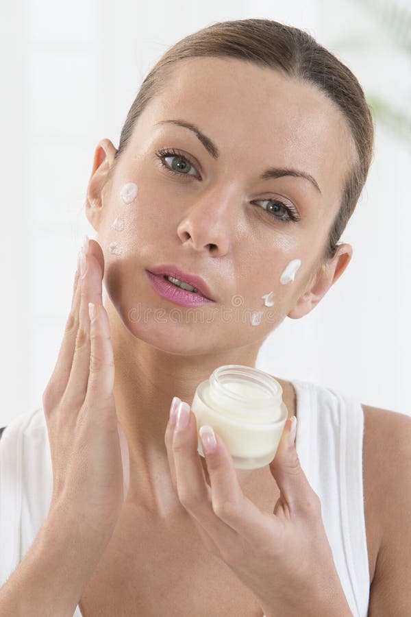 Produtos de Skincare - mulheres bonitas que aplicam o creme hidratante imagem de stock Produtos de Skincare - mulheres bonitas que aplicam o creme hidratante imagem de stock