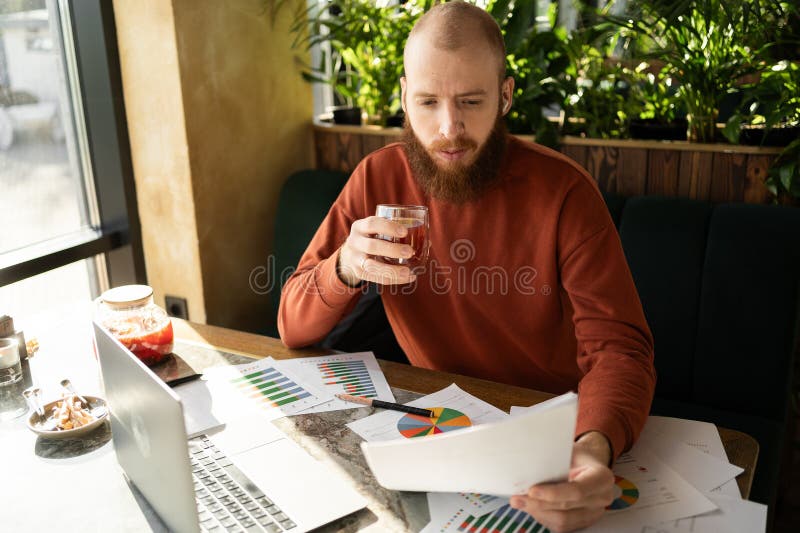 Profesional trabajador a distancia con documentos y laptop trabajando en la moderna oficina de trabajo en interiores imágenes de archivo libres de regalías