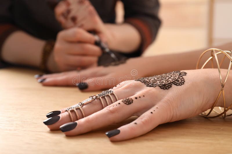 Profesjonalny mistrz mehndi robi tatuaż henny przy stole