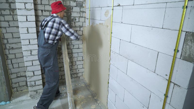 Profesjonalny tynk konstrukcyjny na ścianie bloku za pomocą linijki