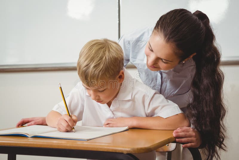 Profesor care ajută un elev din clasă stock photos