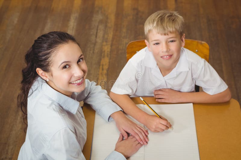 Profesor care ajută un elev din clasă stock photography
