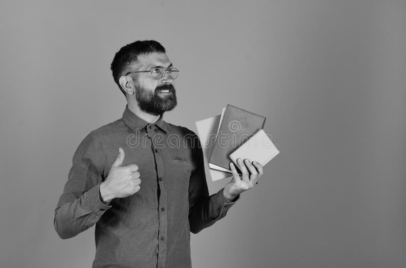 Profesor con los vidrios, el organizador y los pulgares para arriba Hombre con la barba y los libros Profesor con la expresión so fotografía de archivo libre de regalías Profesor con los vidrios, el organizador y los pulgares para arriba Hombre con la barba y los libros Profesor con la expresión so fotografía de archivo libre de regalías