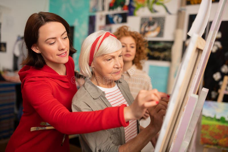 Profesor de arte envejecido y sus estudiantes que ayudan a su dibujo en lona fotos de archivo Profesor de arte envejecido y sus estudiantes que ayudan a su dibujo en lona fotos de archivo