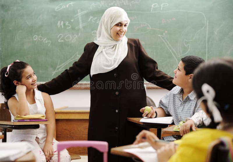 Muslim female teacher with children in classroom in modern school. Muslim female teacher with children in classroom in modern school