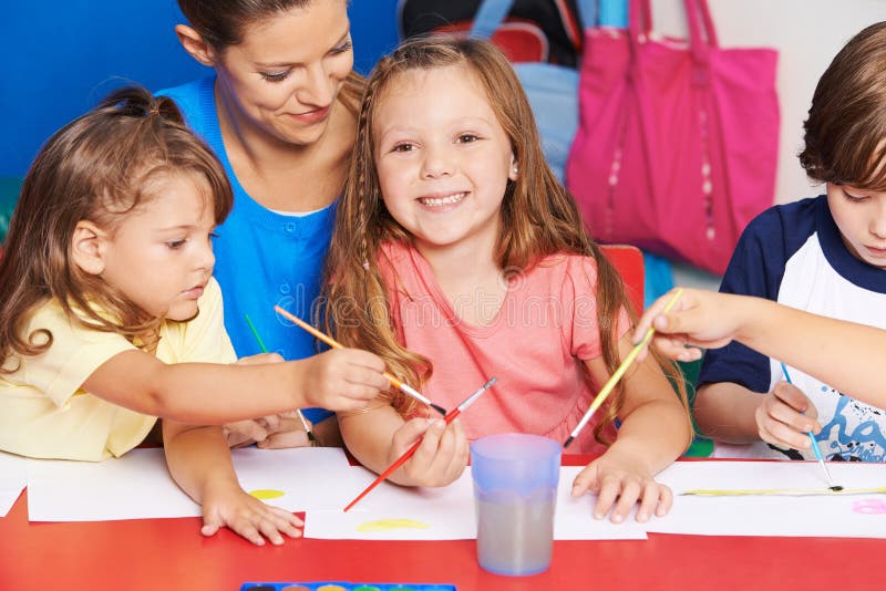 Profesor y niños de arte que pintan en escuela foto de archivo Profesor y niños de arte que pintan en escuela foto de archivo
