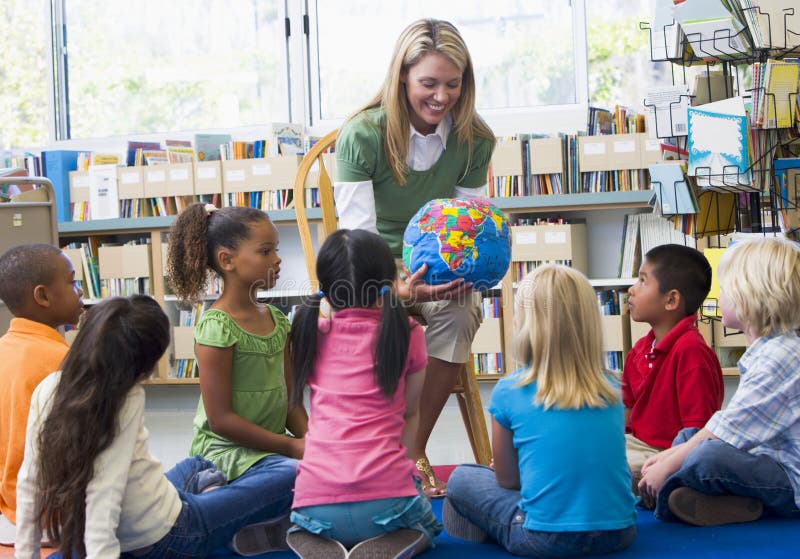 Profesor y niños que miran el globo fotos de archivo Profesor y niños que miran el globo fotos de archivo