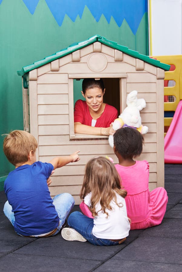 Professeur de crèche employant la maison de théâtre pour le jeu de théâtre image libre de droits Professeur de crèche employant la maison de théâtre pour le jeu de théâtre image libre de droits