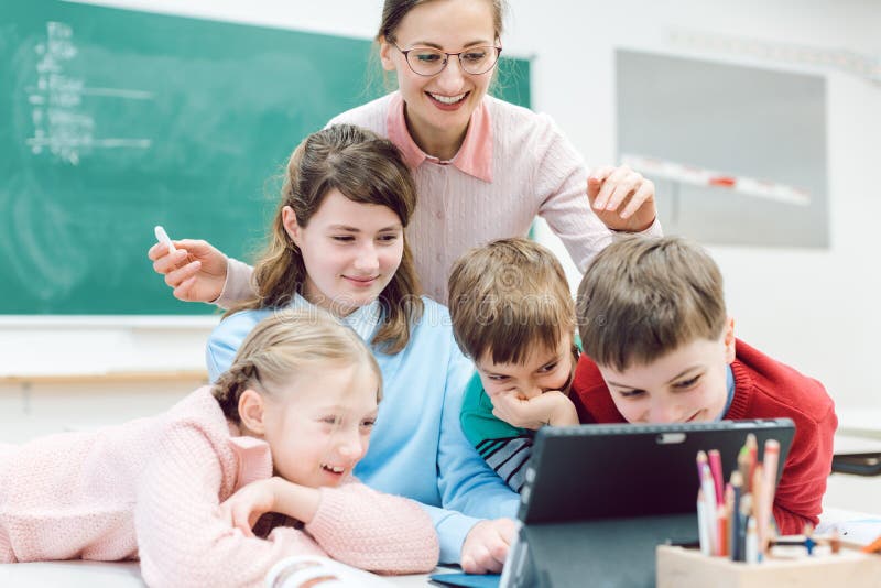 Teacher and students using media and technology in classroom watching educational film. Teacher and students using media and technology in classroom watching educational film