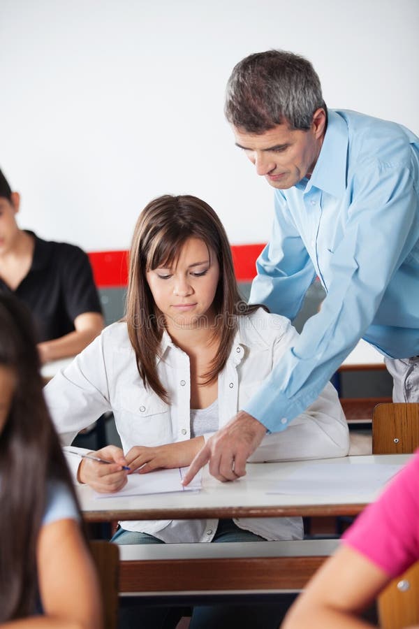 Professeur masculin Assisting Female Student au bureau photo libre de droits