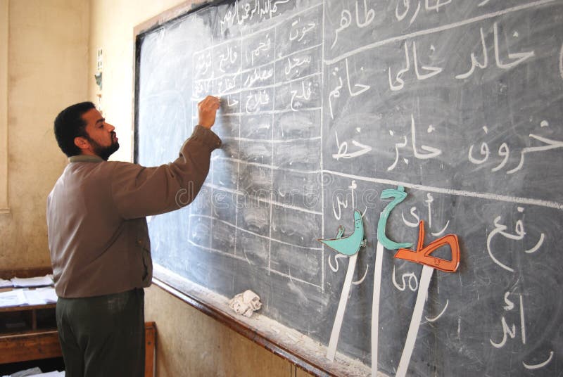 Professeur masculin dans la chambre de classe écrivant l'arabe sur le tableau noir