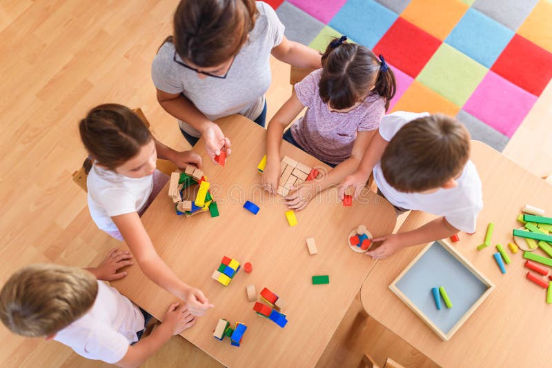 Professeur préscolaire avec des enfants jouant avec les jouets didactiques en bois colorés au jardin d'enfants photos stock Professeur préscolaire avec des enfants jouant avec les jouets didactiques en bois colorés au jardin d'enfants photos stock