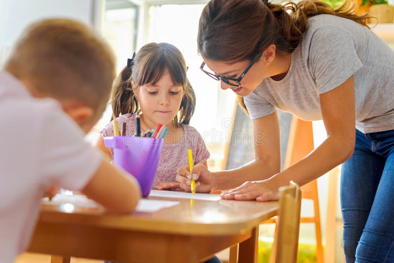 Preschool teacher looking at smart child learning to write and draw. Early education. Harnessing creativity and support. Preschool teacher looking at smart child learning to write and draw. Early education. Harnessing creativity and support.