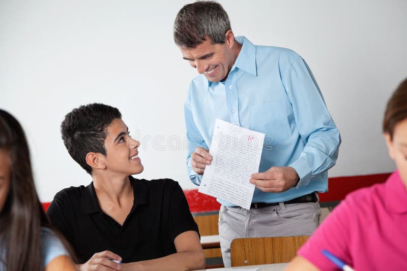 Professeur And Schoolboy Looking au papier pendant image libre de droits Professeur And Schoolboy Looking au papier pendant image libre de droits