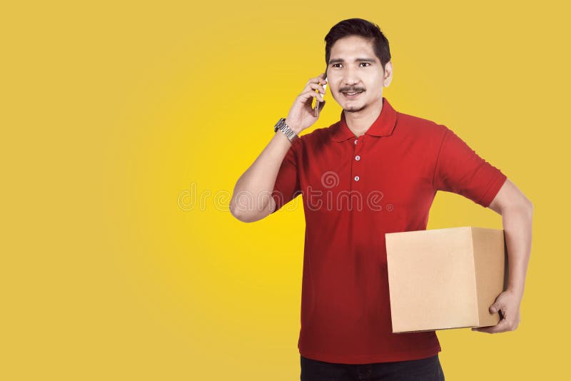 Professional asian delivery man using phone while carrying parcel stock photography Professional asian delivery man using phone while carrying parcel stock photography