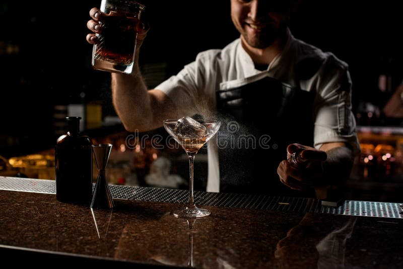Professional Bartender Spraying on the Brown Alcoholic Drink with a