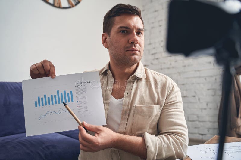 Serious male entrepreneur with a pen in his hand showing a profit growth bar chart. Serious male entrepreneur with a pen in his hand showing a profit growth bar chart