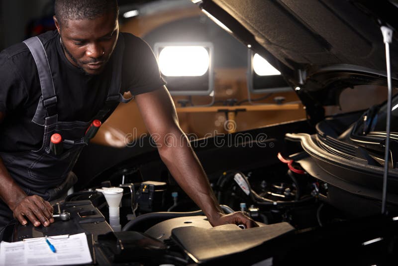 Professional Car Mechanic is Examining Engine Under the Hood at Auto