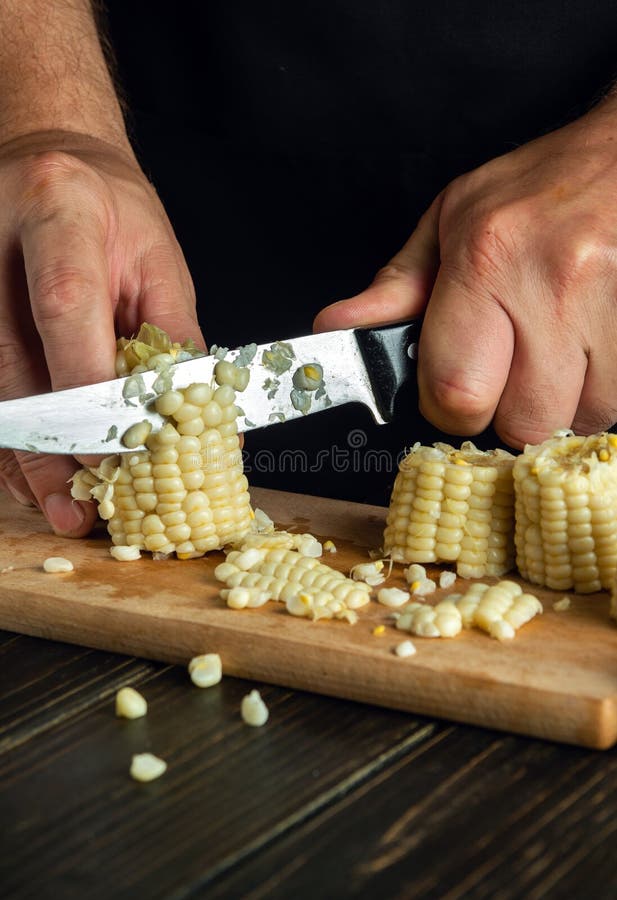 Professional Chef Cuts the Boiled Maize with a Knife. Corn is an