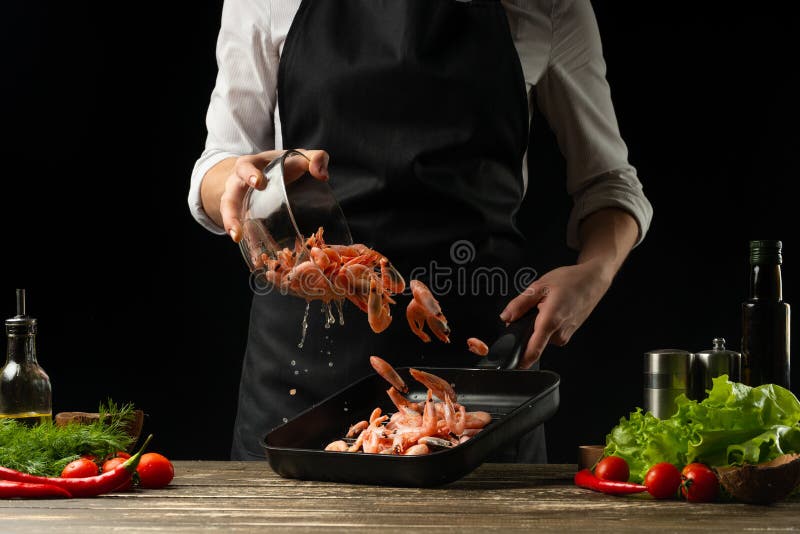 Professional chef prepares a salad of fresh shrimp, and vegetables on a dark background, freezing in motion. Seafood and healthy royalty free stock images Professional chef prepares a salad of fresh shrimp, and vegetables on a dark background, freezing in motion. Seafood and healthy royalty free stock images