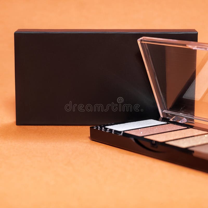 Professional colorful eye shadows for make up in plastic box on orange background. Mock up image with space for text stock image