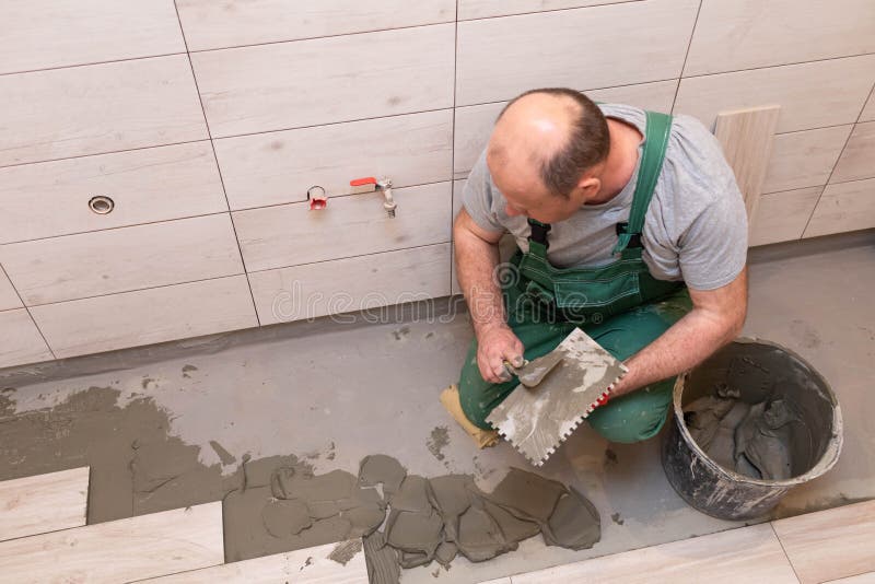 Free Photo  Builder checks the quality of the laid tiles with a manual  bubble level construction worker installing ceramic floor tiles on  construction sites floor repair selective focus