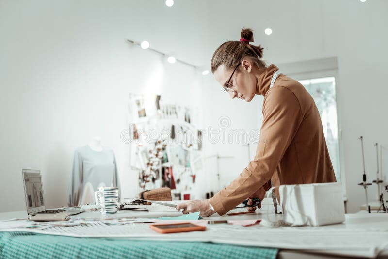 Professional designer from a fashion studio in a brown garment looking concentrated