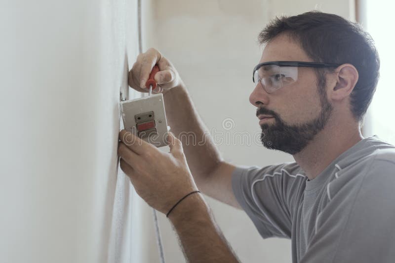 Professional electrician installing sockets using a screwdriver: home renovation and maintenance concept. Home electrician stock images, royalty-free photos and pictures