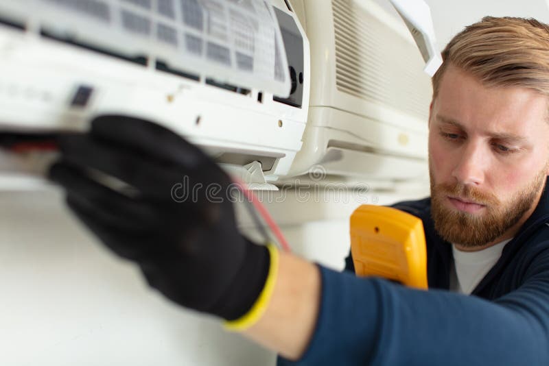 Professional Electrician Man Fixing Heavy Air Conditioner Stock Photo