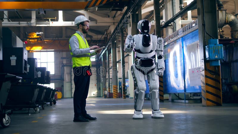 Professional engineer controls a robot, typing on a tablet. stock video