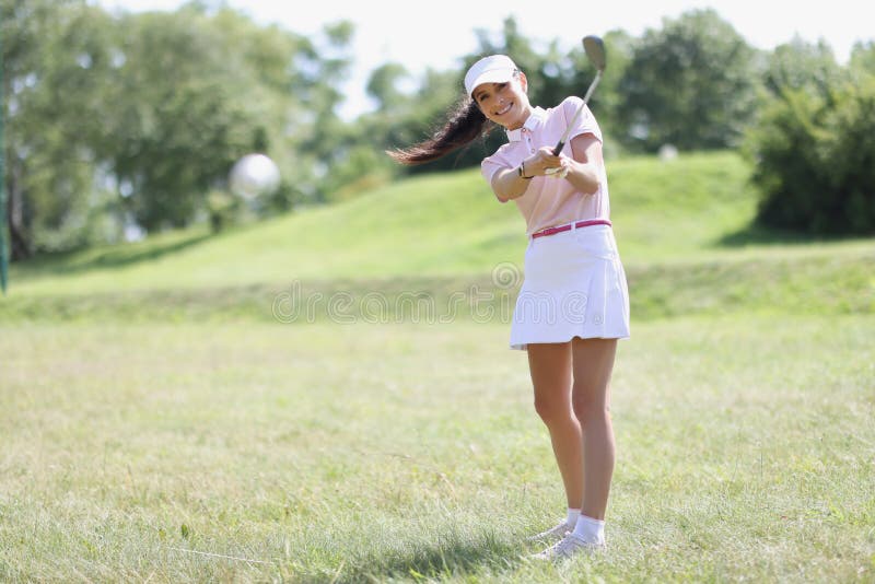 Professional female golf player hit ball with golf club on field