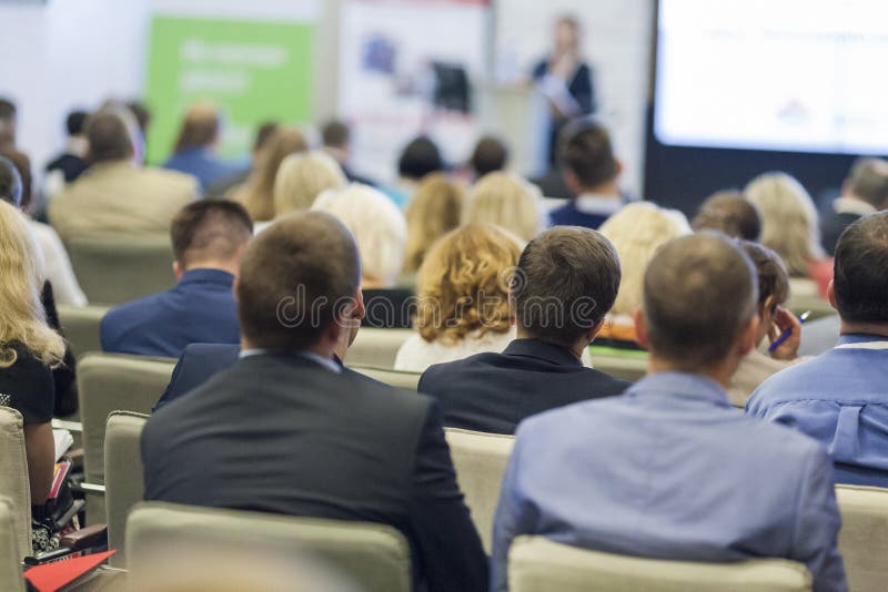 Professional Female Host Speaking in Front of the Large Audience During Business Conference. royalty free stock images