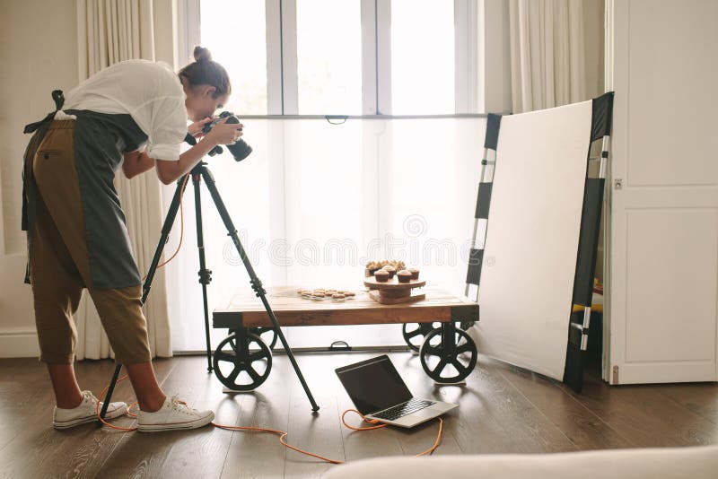 Professional food blogger taking pictures of pastry items on table with dslr camera. Female photographer taking pictures of sweet food, camera mounted on tripod with laptop on floor. Professional food blogger taking pictures of pastry items on table with dslr camera. Female photographer taking pictures of sweet food, camera mounted on tripod with laptop on floor