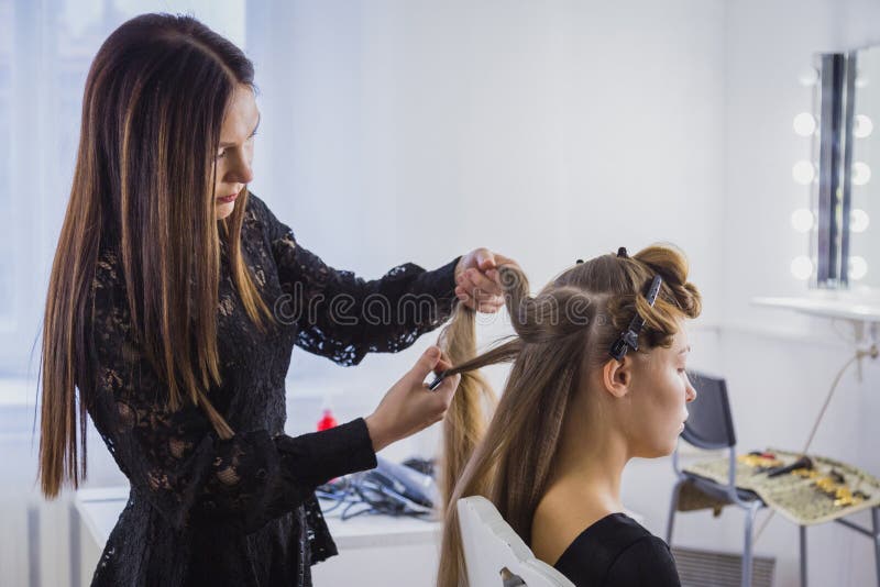 Professional hairdresser doing hairstyle for young pretty woman with long hair royalty free stock photography Professional hairdresser doing hairstyle for young pretty woman with long hair royalty free stock photography