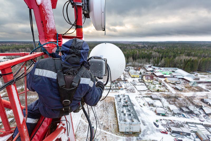 Professional industrial climber in uniform and climber equipment on the telecommunication tower is installing outdoor stock images Professional industrial climber in uniform and climber equipment on the telecommunication tower is installing outdoor stock images